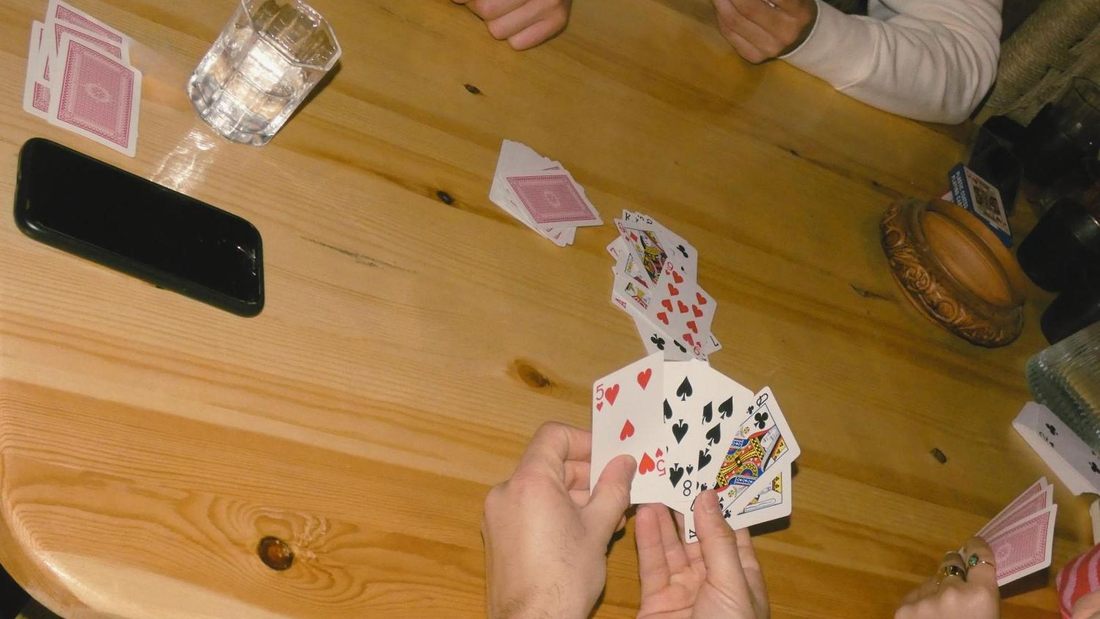 Hands playing cards next to glasses of mint tea on a surfboard table