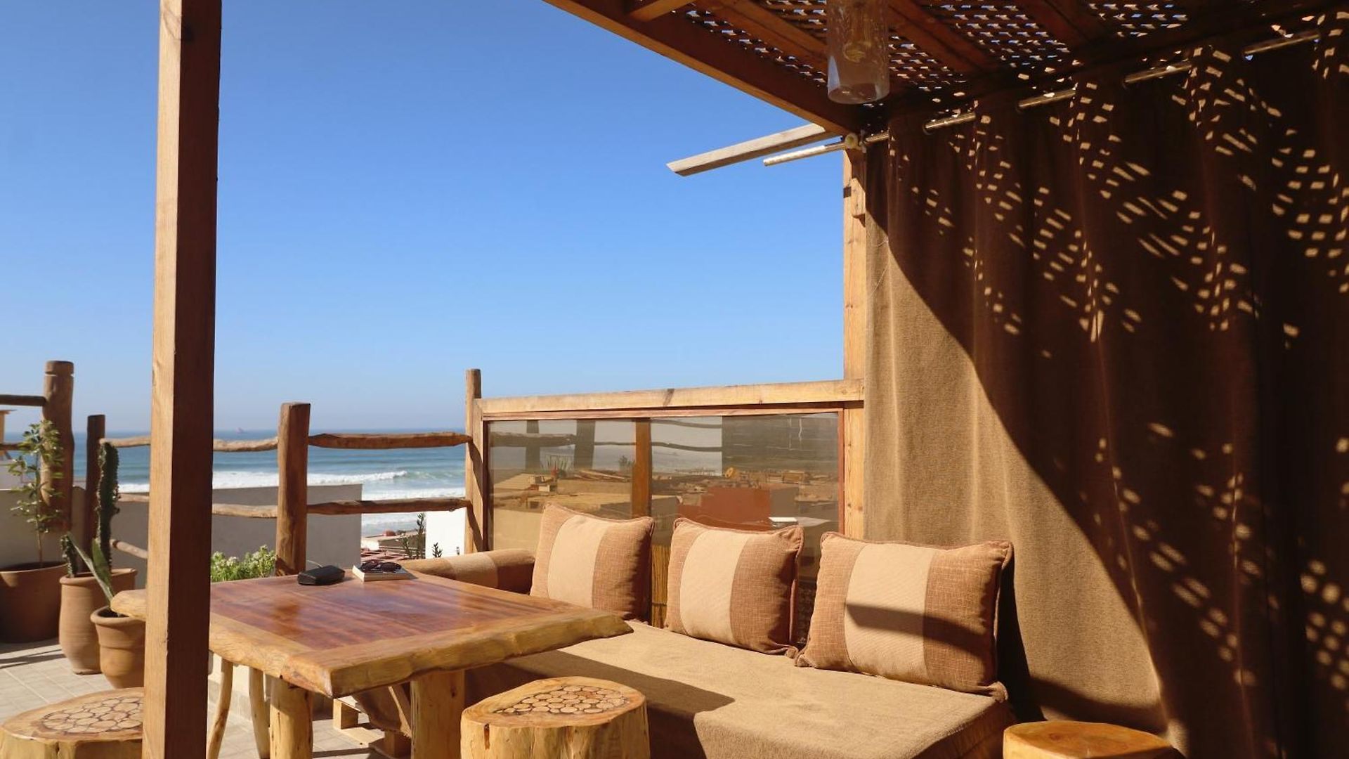 Rooftop lounge under the pergola with cushions and ocean view