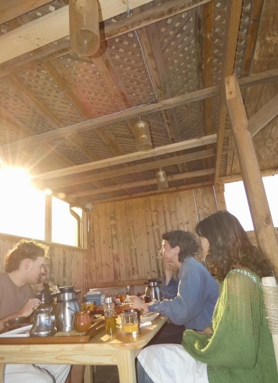 Long shared dinner table under the rooftop pergola at golden hour