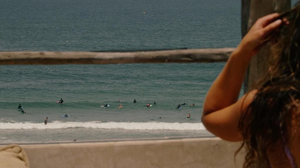 Surfers in the lineup at Anza Beach, seen over the surfhouse rooftop rail
