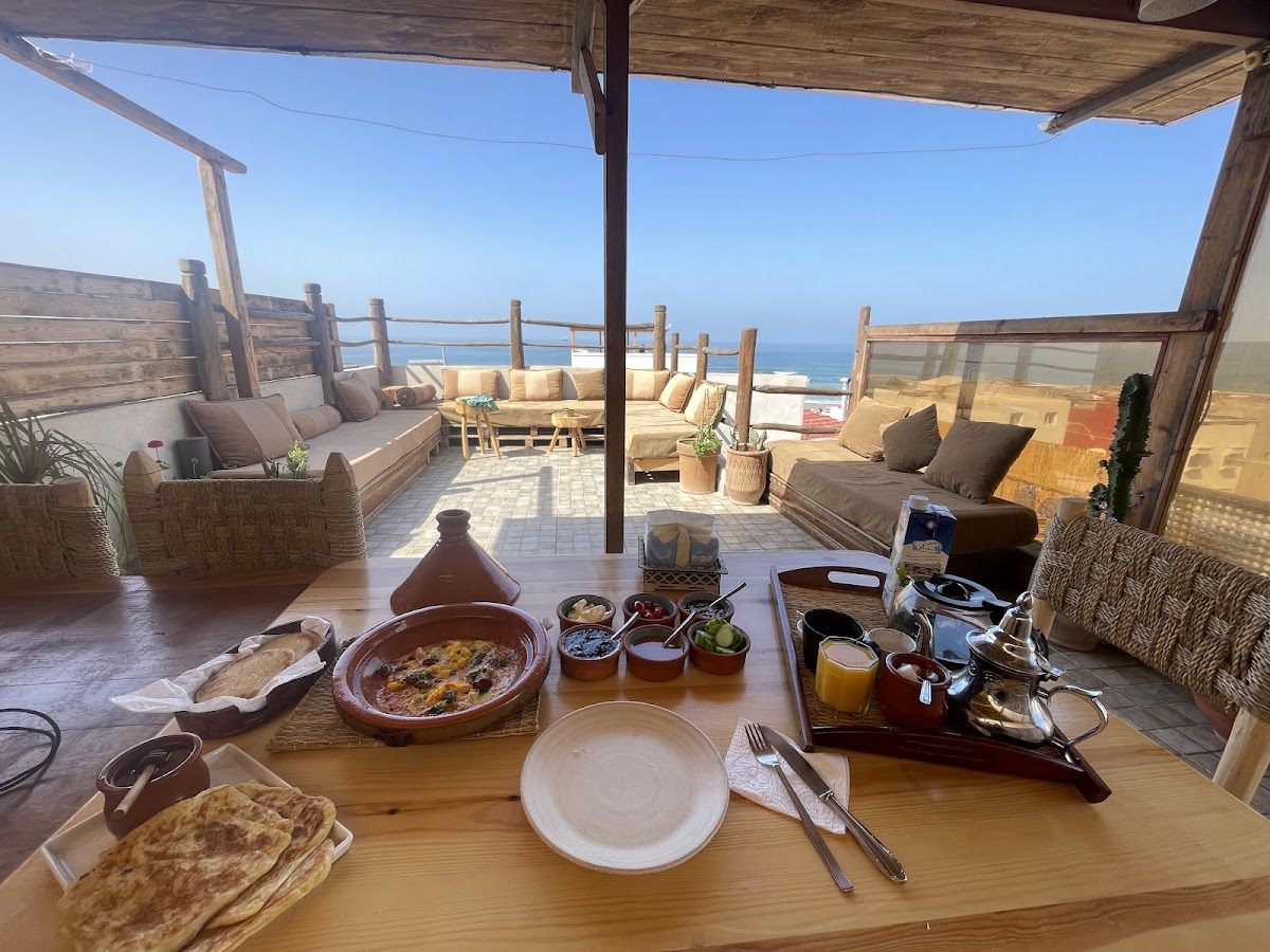 Tagine, fresh bread and a tea tray on the rooftop table, ocean in the background