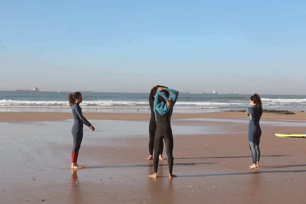 Three surfers in wetsuits warming up on Anza beach