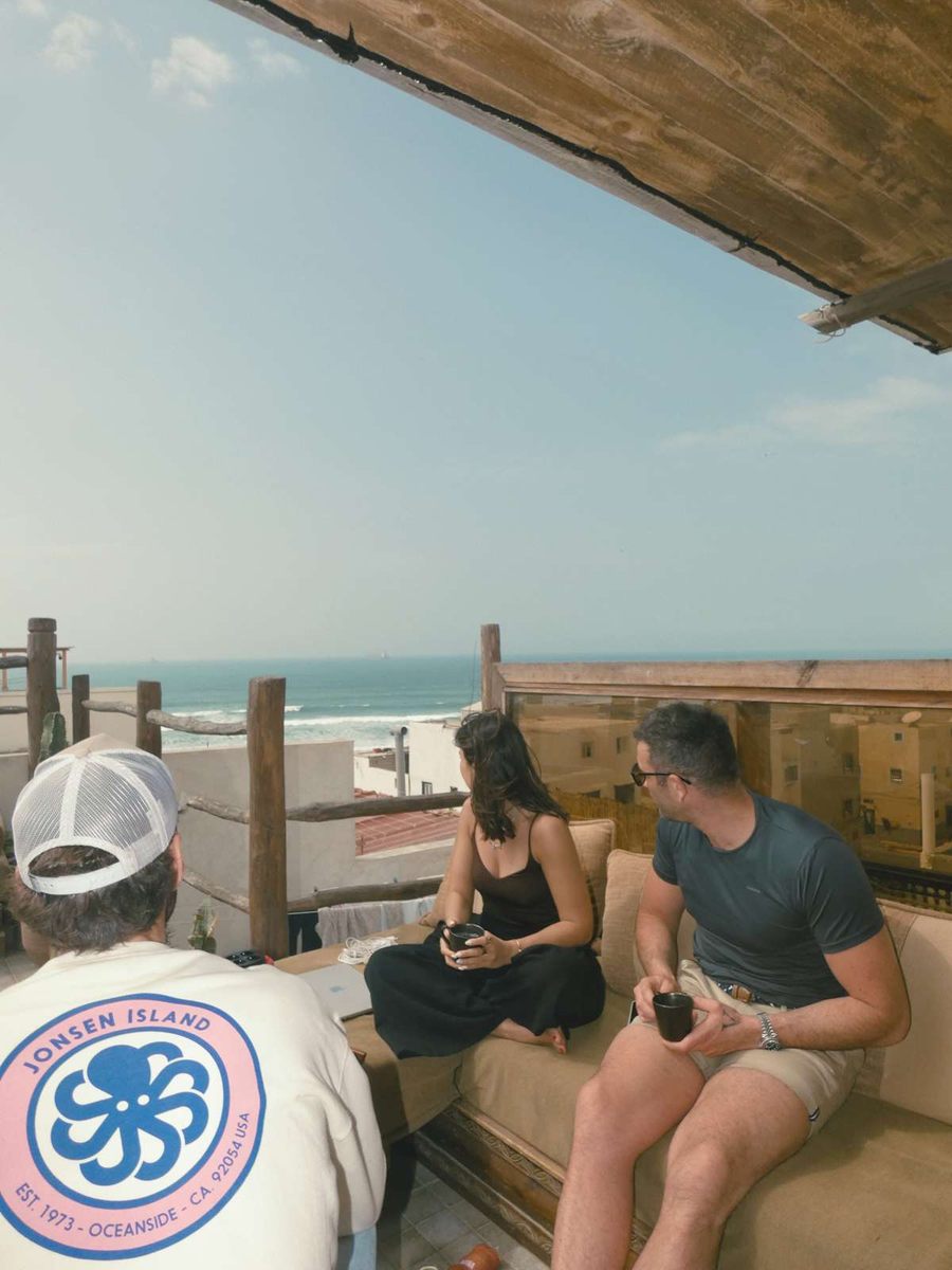 Guests chatting on the rooftop with the beach below